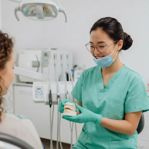 Chirurgien-dentiste expliquant un soin à une patiente au cabinet dentaire