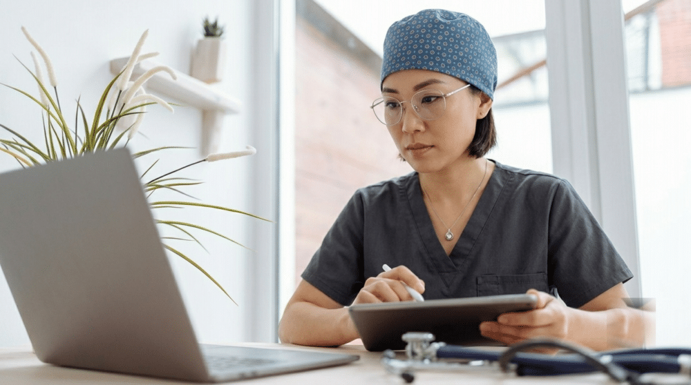 Femme médecin gérant l'administratif de son cabinet sur ordinateur et tablette