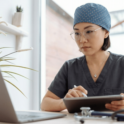 Femme médecin gérant l'administratif de son cabinet sur ordinateur et tablette