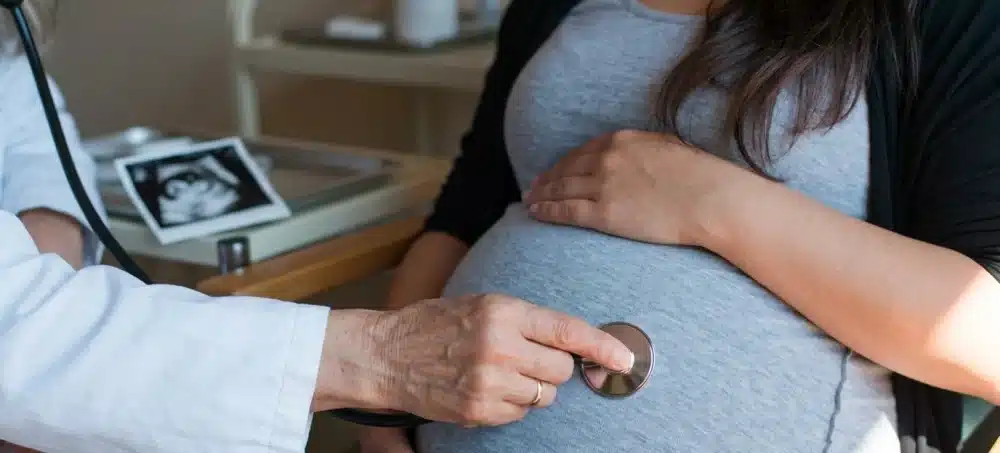 sage femme qui osculte une femme enceinte